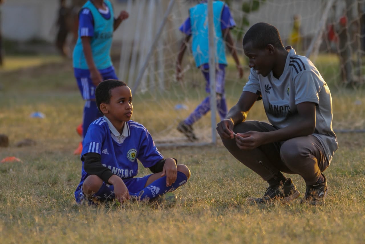 A coach talking to young Rangers players during training